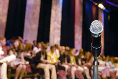 Image of a microphone with an audience in the background